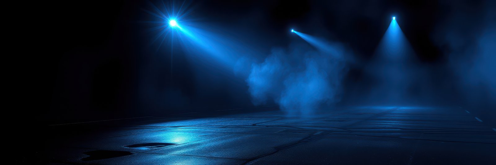 Blue spotlights illuminate a stage with smoke and a reflective floor